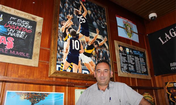 Anthony Pavlou stands proudly beside his painting of Alex Jesaulenko's moment of brilliance against Richmond in the 1972 semi-final replay. (Photo: Carlton Media)